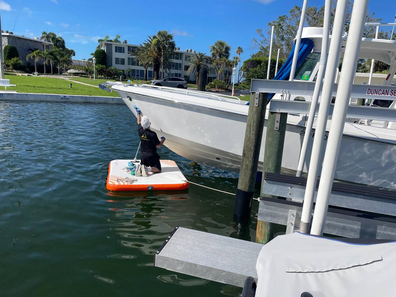 Technician washing the side of a center console from a floating platform